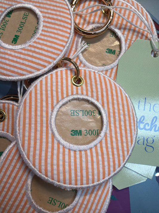 Round orange and white striped fabric tags with gold rings