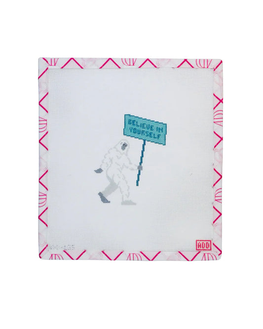 Notebook with a design of a person in a spacesuit holding a 'Believe in Yourself' sign, on a white background with pink geometric patterns.