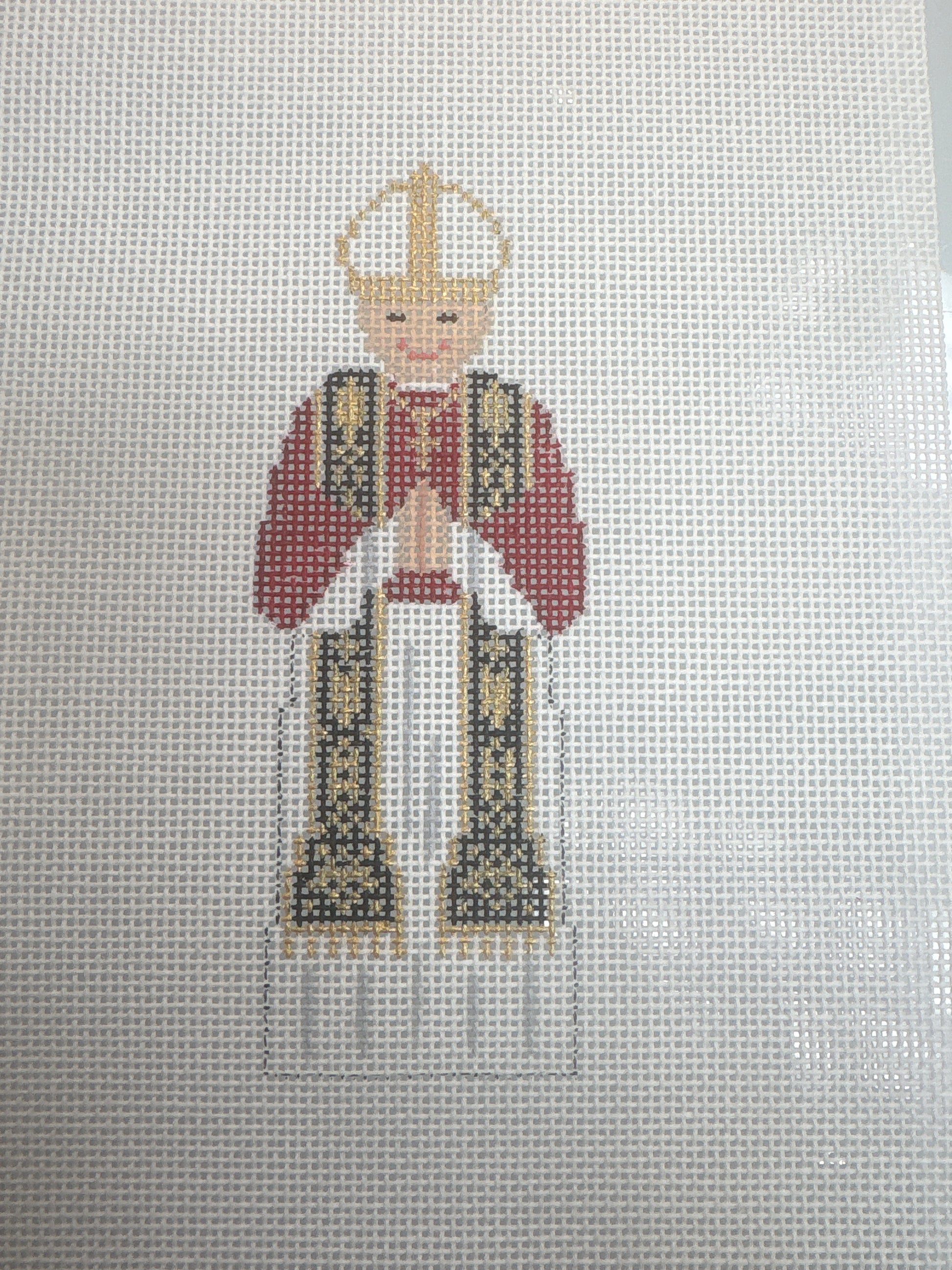 Embroidered design of a religious figure with a red robe and gold crown.