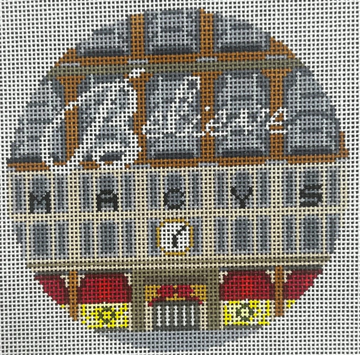 Cross-stitched design of a building with decorative elements on a grid background