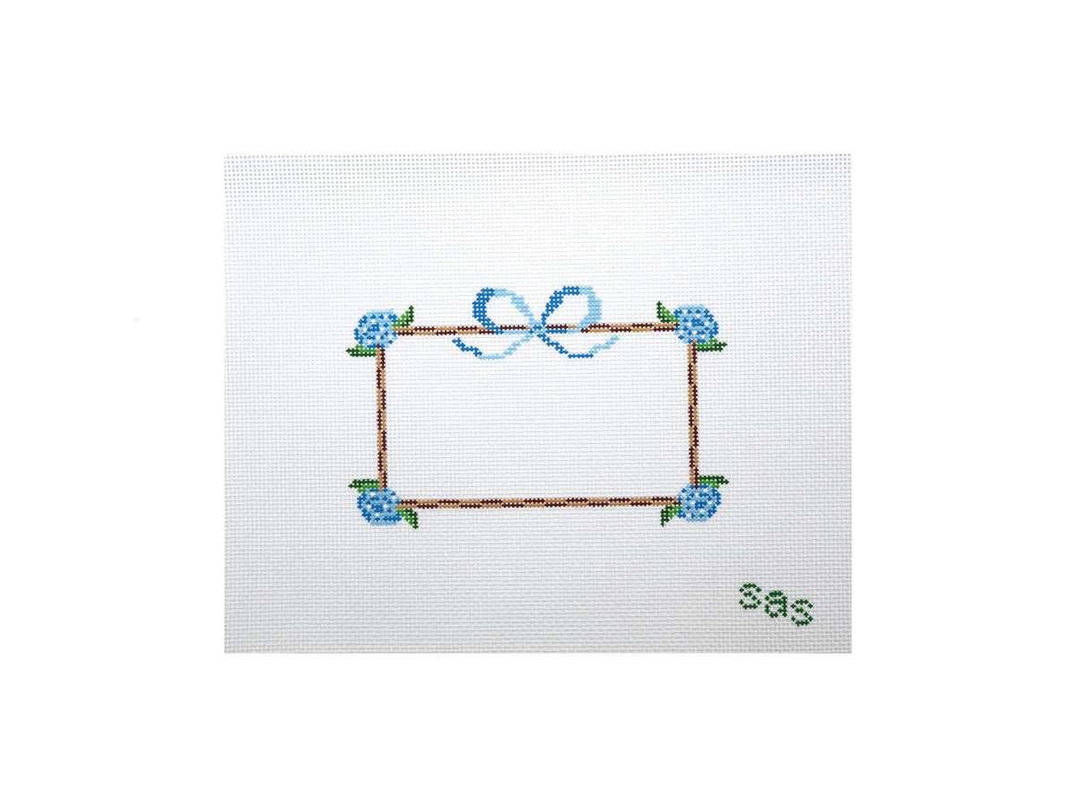Cross-stitched frame with blue flowers and a bow on a white background