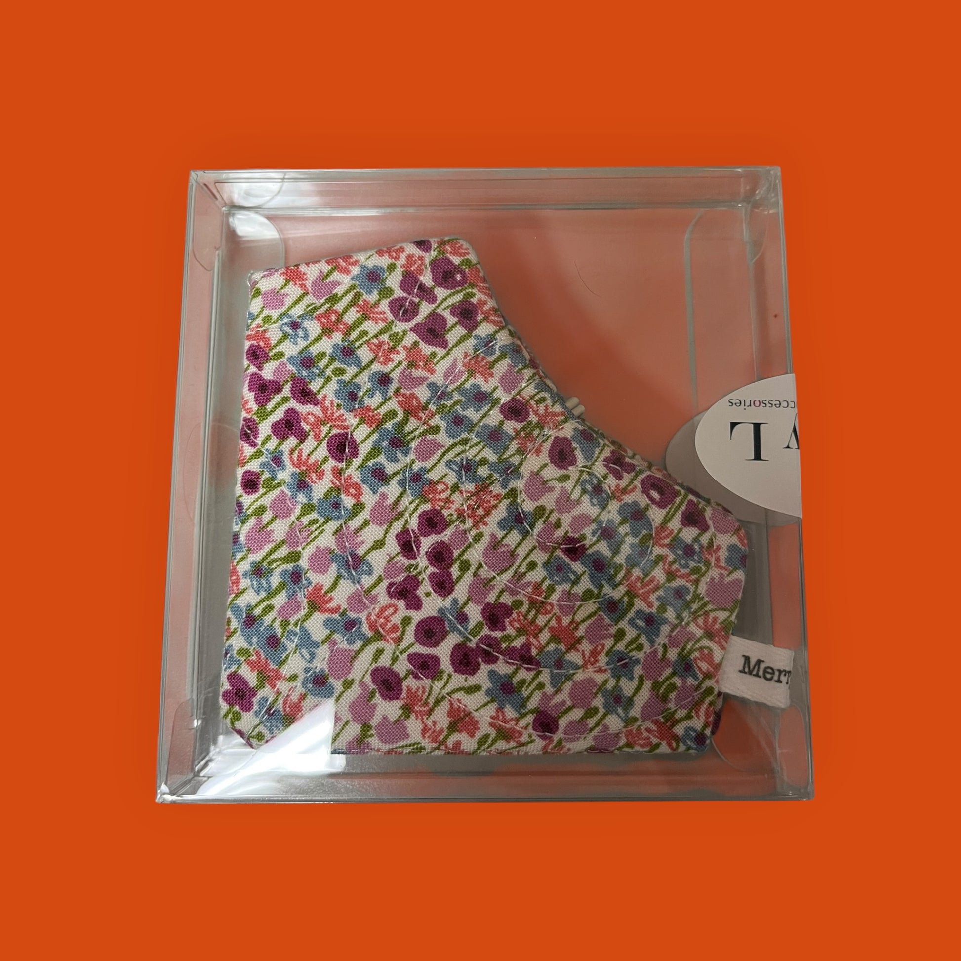 Floral-patterned product in clear packaging on an orange background