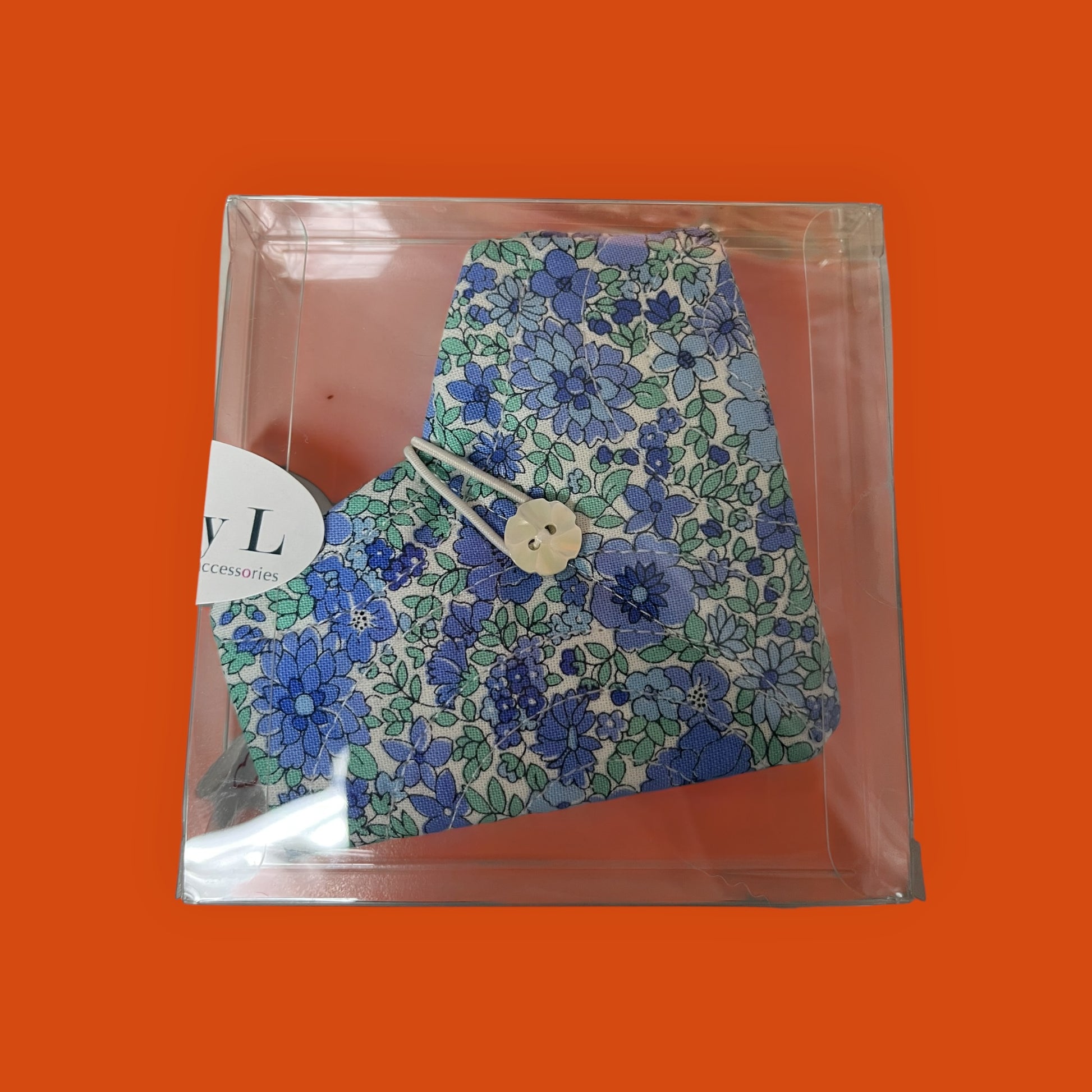 Floral-patterned product in clear packaging on an orange background