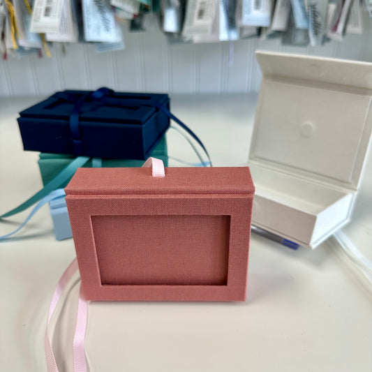 Pink jewelry box on a table with other boxes in the background