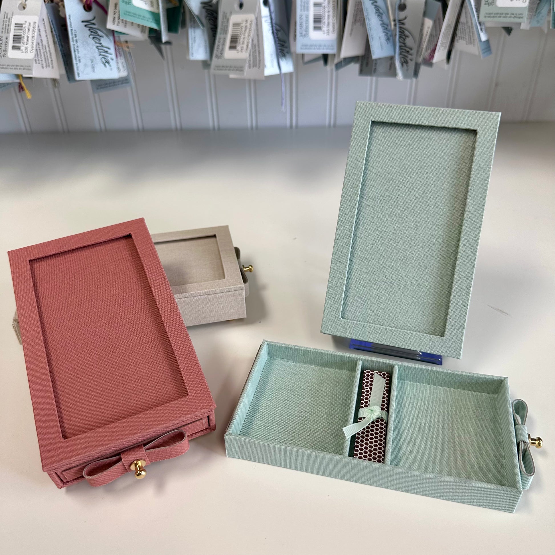 Three jewelry boxes in different colors on a light surface with a neutral background.