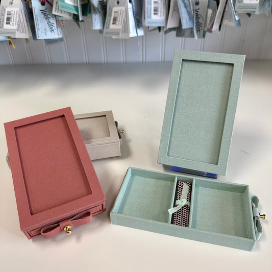 Three jewelry boxes in different colors on a light surface with a neutral background.