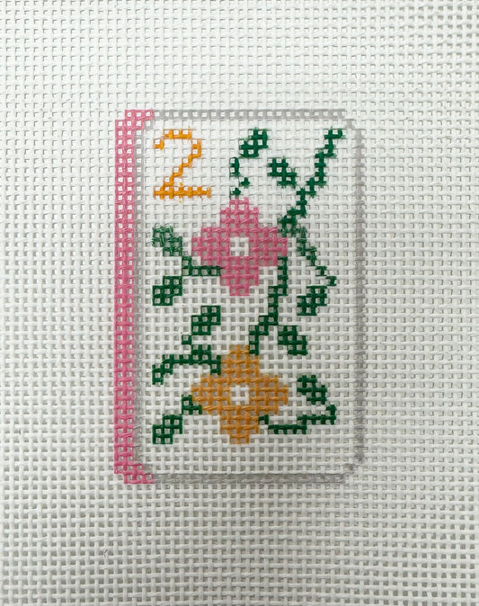 Cross-stitched number '2' with flowers on fabric