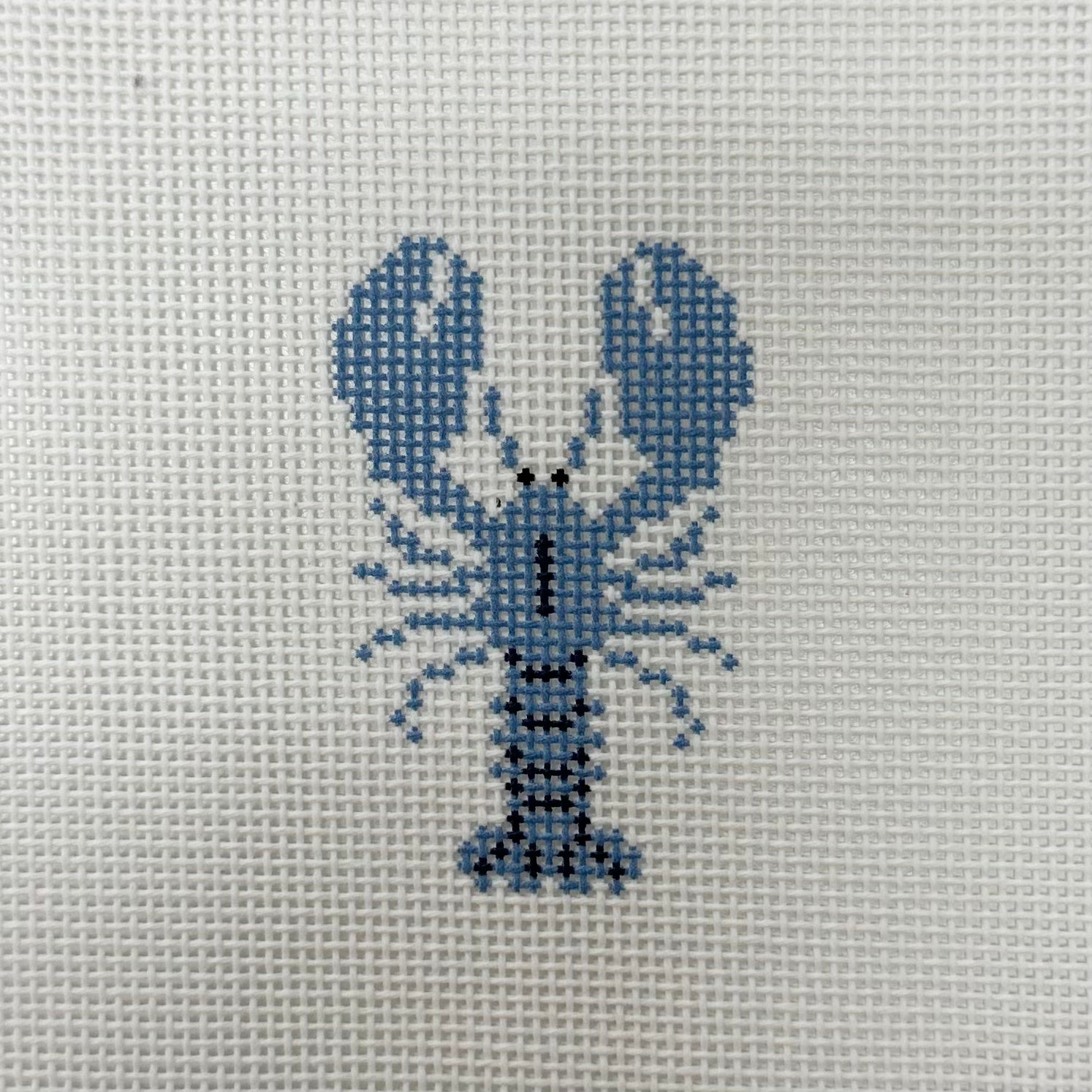 Cross-stitched lobster design on a fabric background