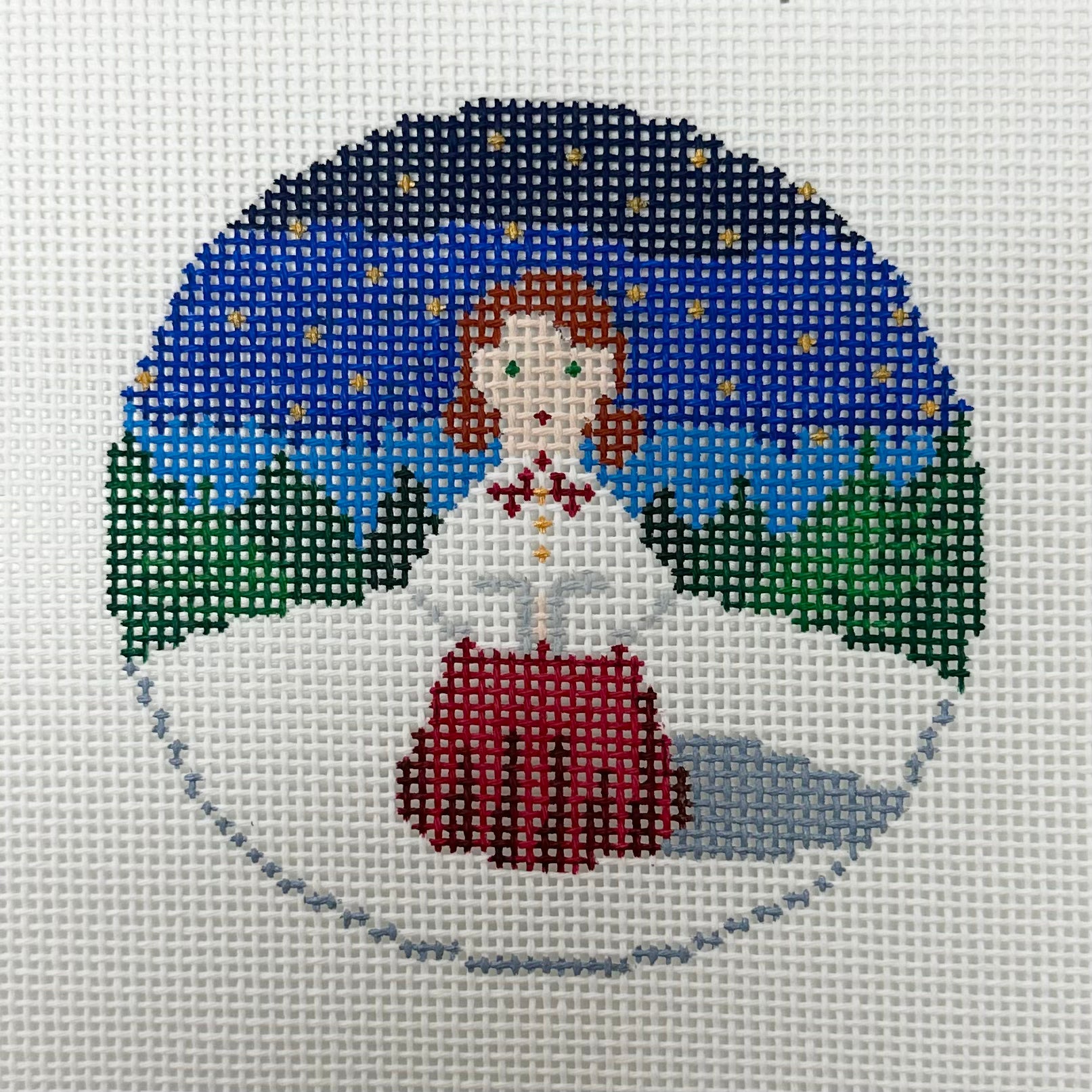Cross-stitched design of a woman in a snowy landscape with a blue sky.