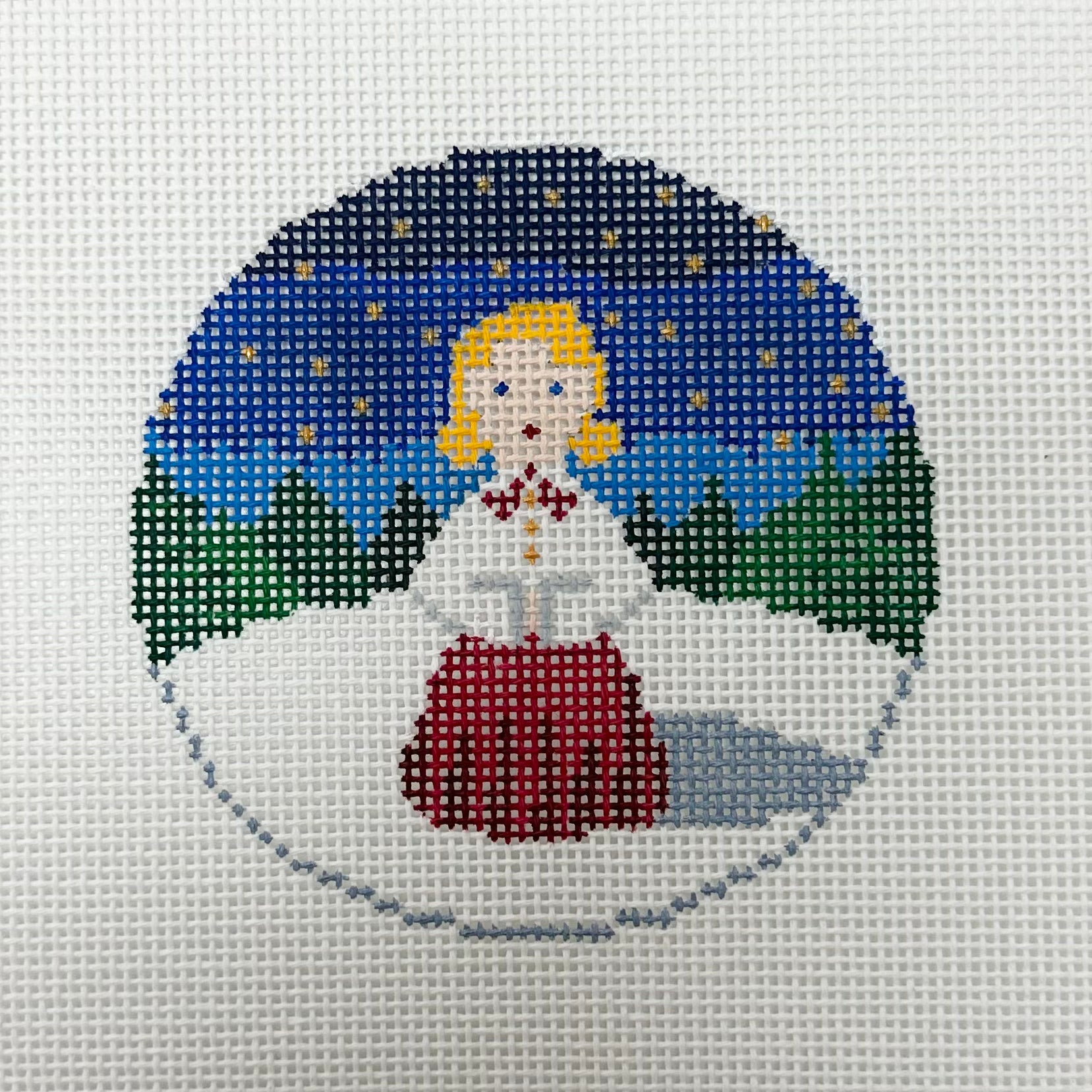 Cross-stitched design of a fairy in a snowy landscape with a blue sky.