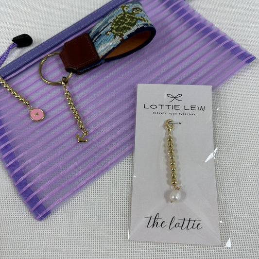 Gold chain charms with pearl on a Lottie Lew card, placed on a purple fabric background.