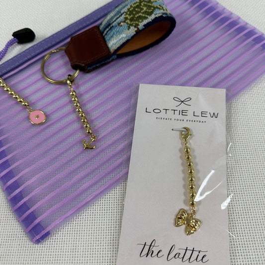 Gold keychain with pink charm on a purple striped background, featuring Lottie Lew branding.