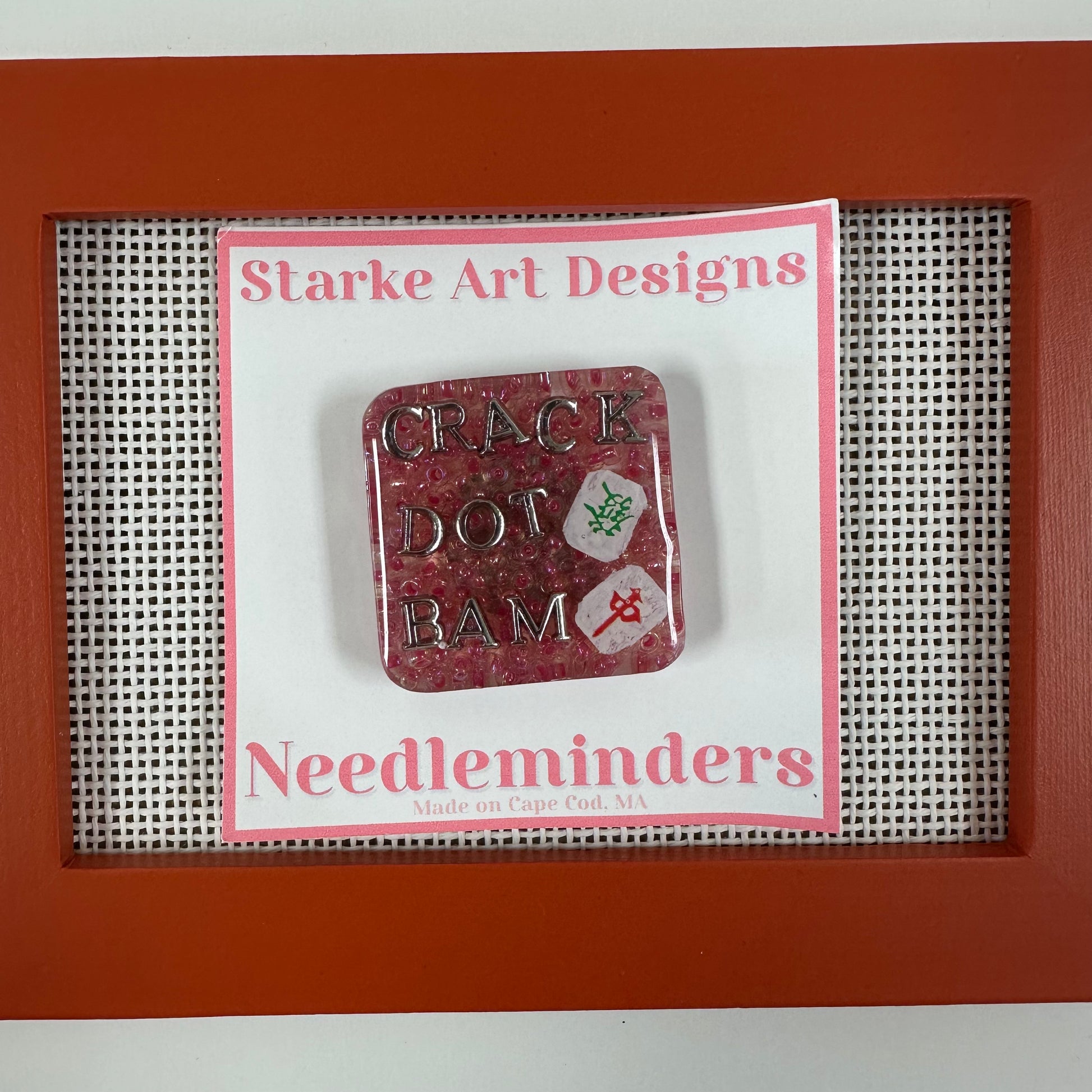 Red needle minder with text on a Starke Art Designs card in a red frame.