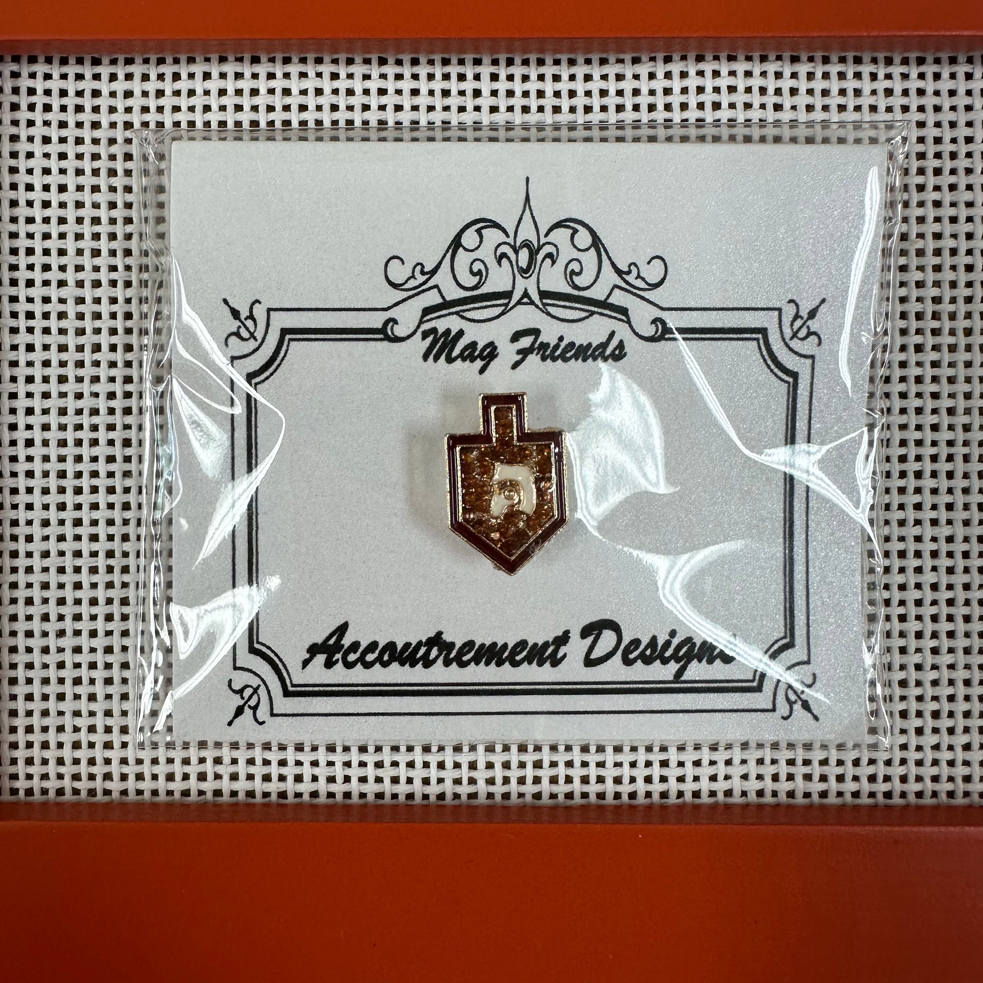 Pin on a card with 'Accoutrement Designs' branding, enclosed in clear plastic.