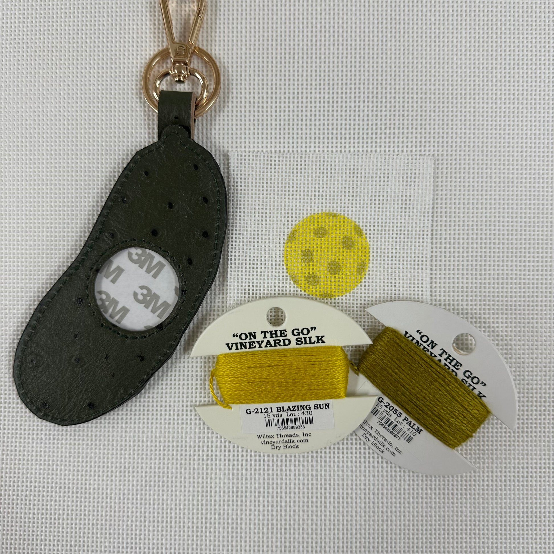 Black leather keychain with 'On the Go' Vineyard Silk thread packaging on a light gray background