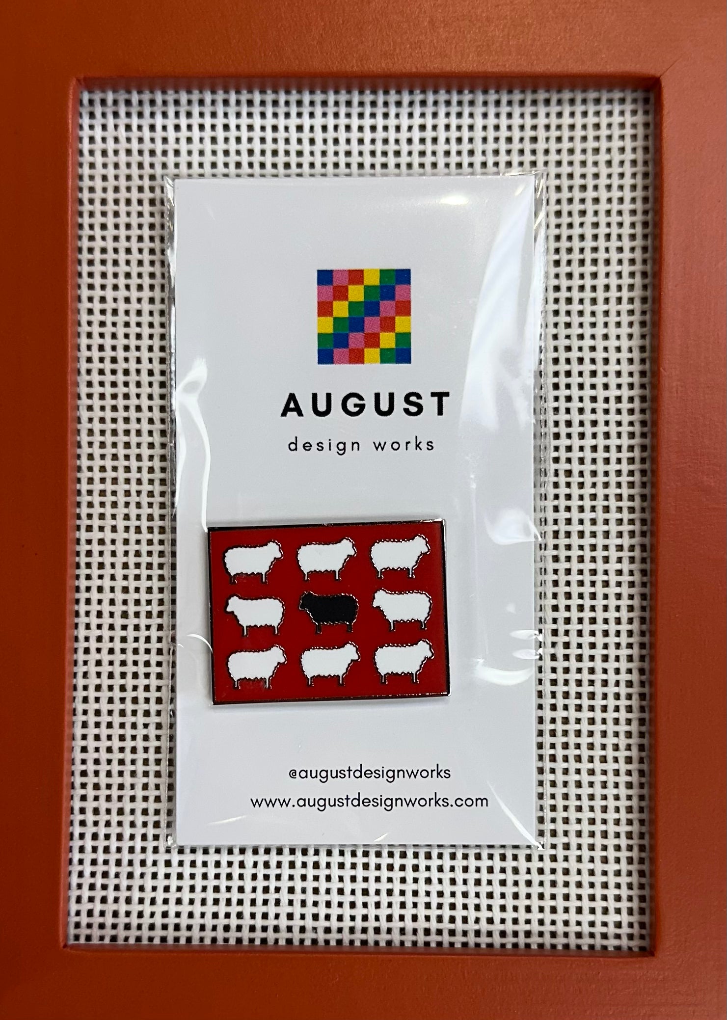 Packaged product with 'August Design Works' branding on a cross-stitch background