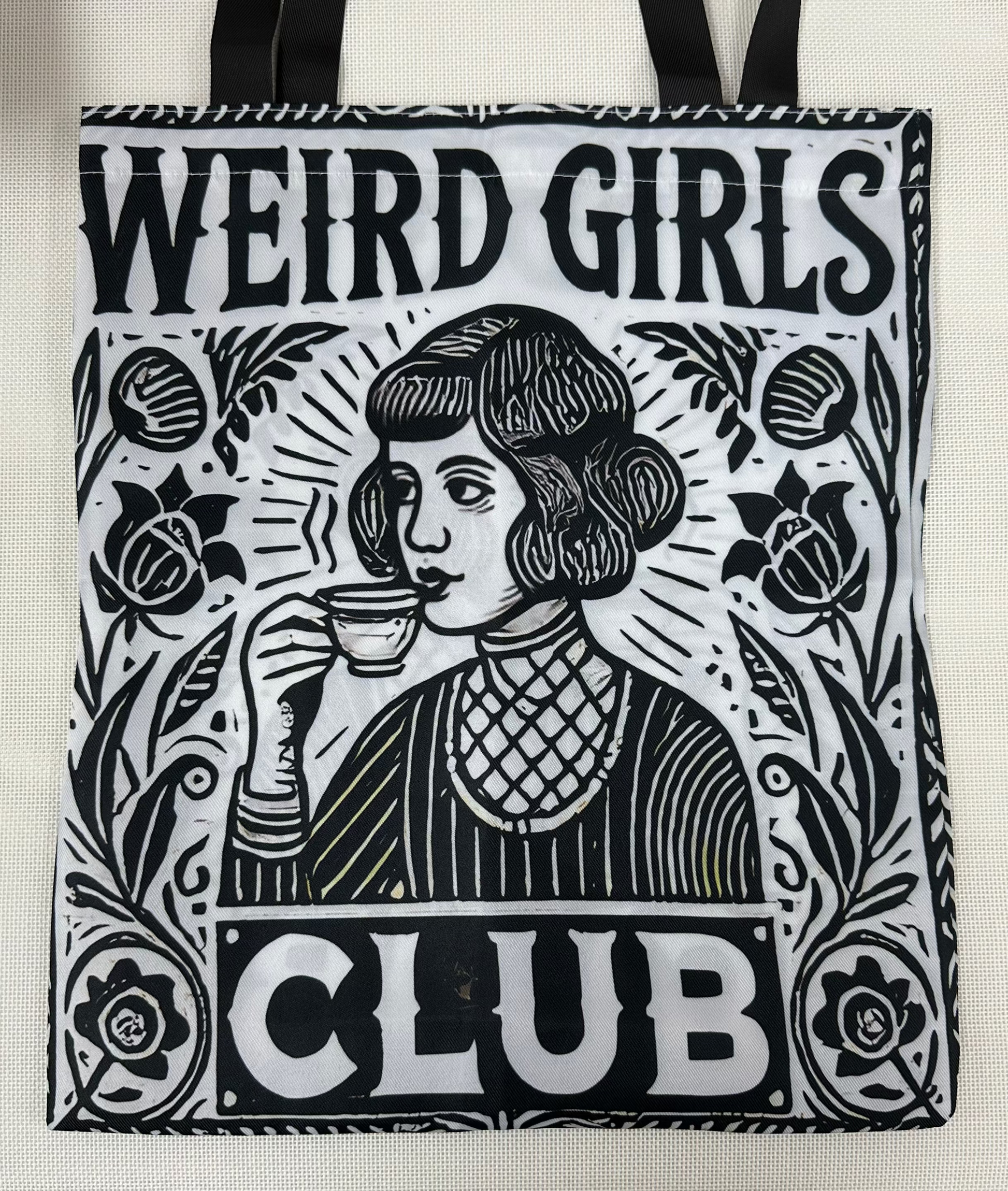 Tote bag with 'Weird Girls Club' design featuring a woman drinking from a cup.