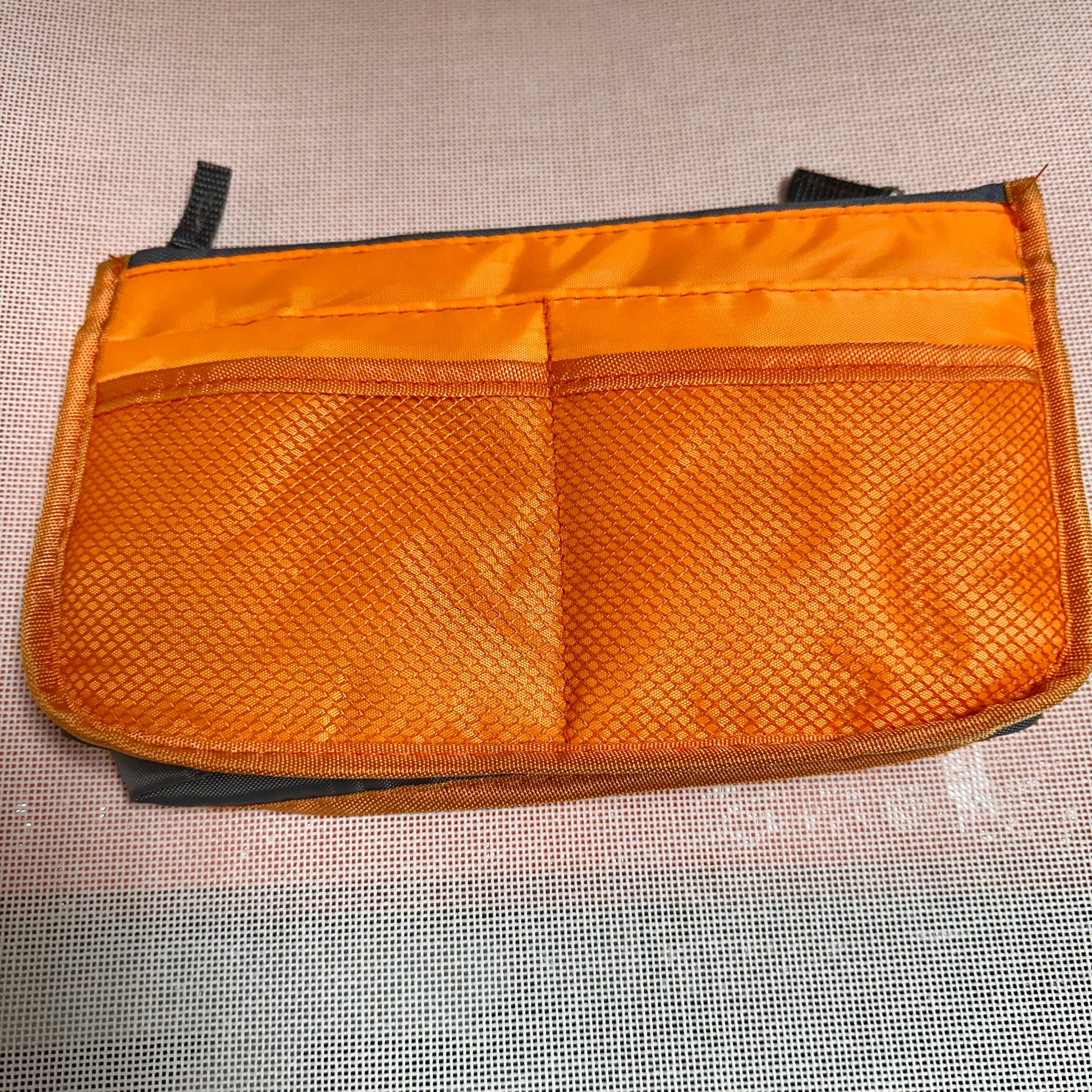 Orange mesh pouch with a zipper on a textured surface