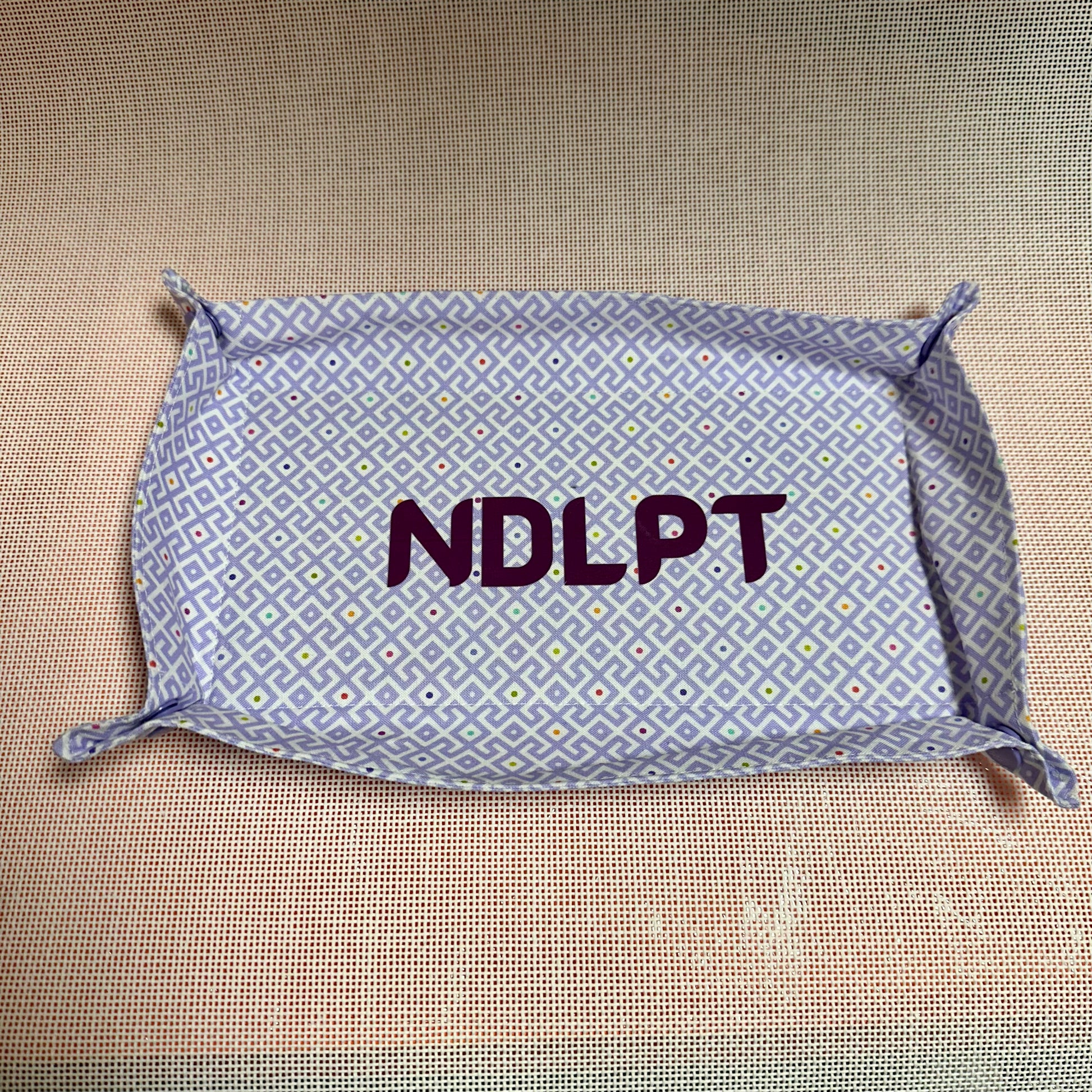 Fabric tray with 'NDLPT' text on a textured surface