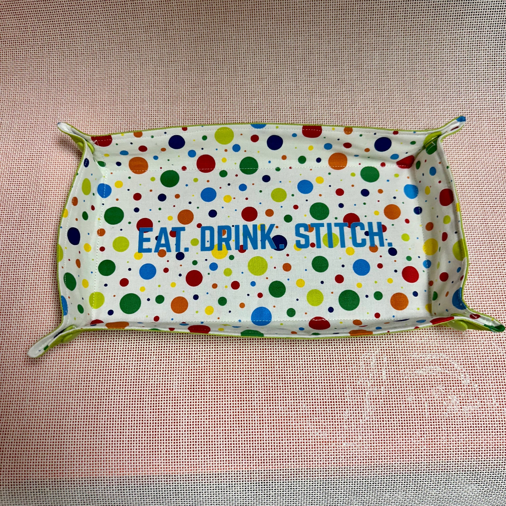 Polka dot fabric with 'Eat Drink Stitch' text on a pink background
