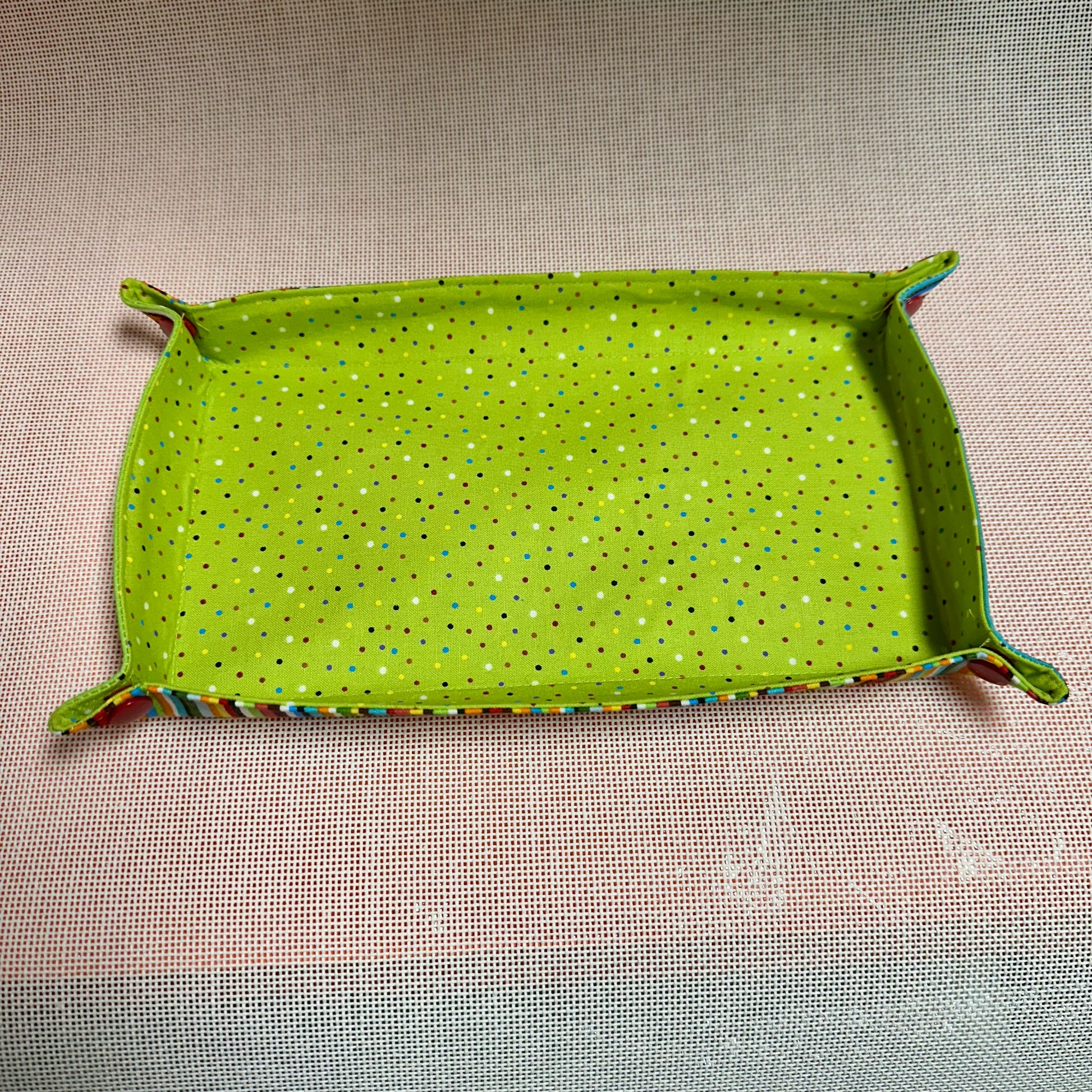 Green fabric tray with a pattern on a beige surface