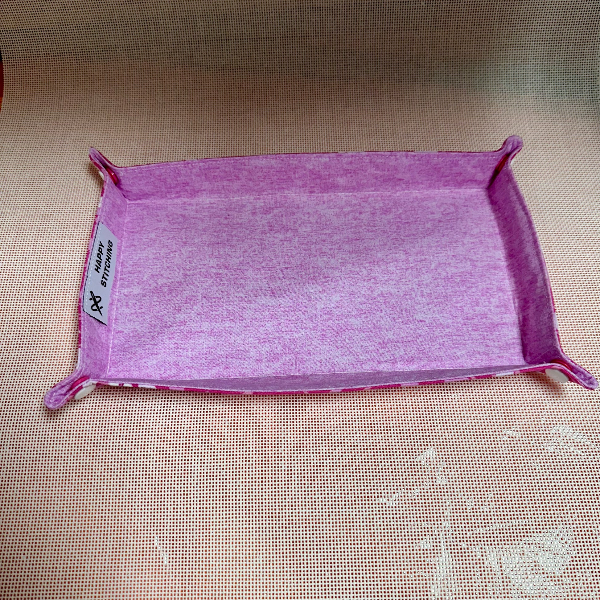 Purple fabric tray with a label on a beige surface