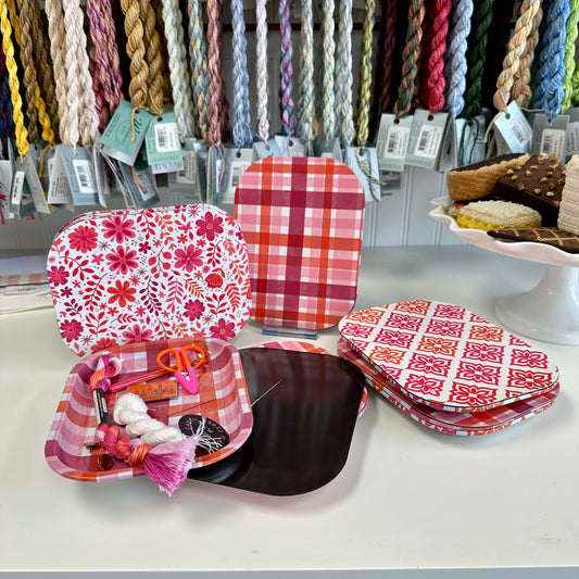 Colorful plates with patterns and a small box of sewing supplies on a table.