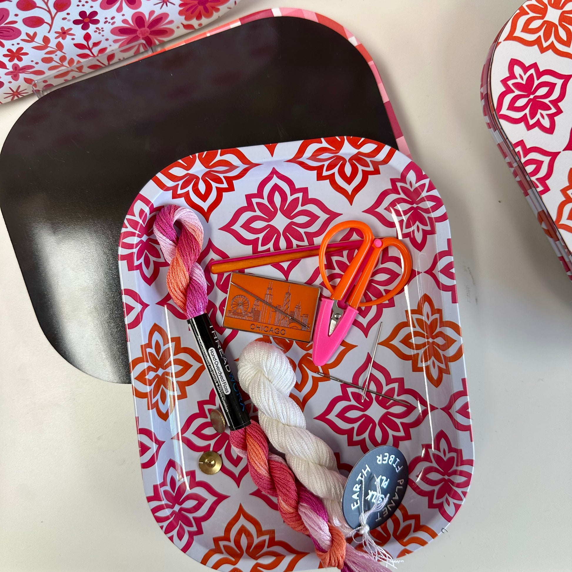 Decorative tray with yarn, scissors, and other crafting items on a white background