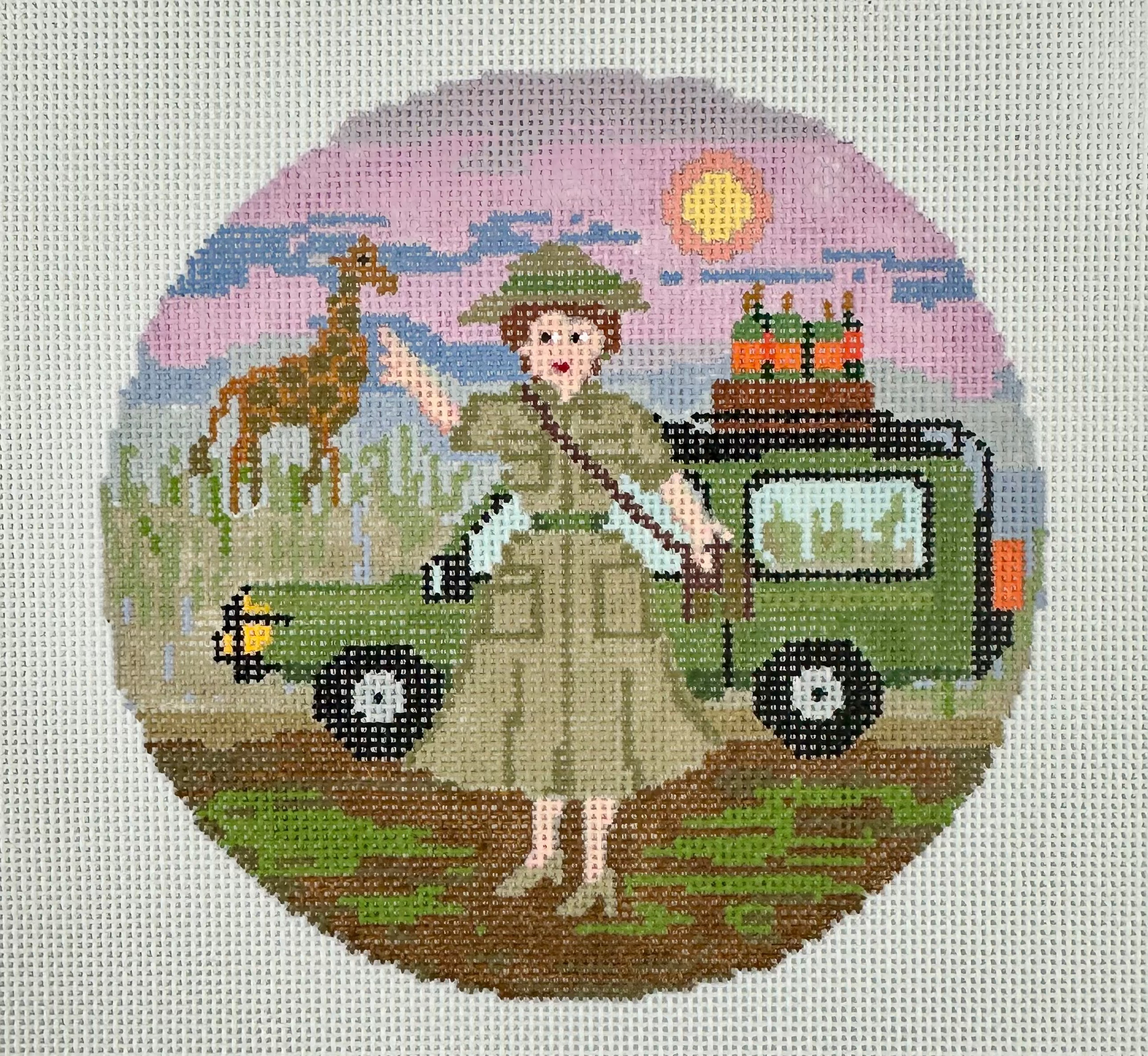 A circular needlepoint canvas featuring a safari-themed design with a woman in a khaki uniform.
