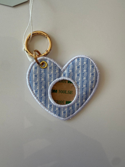 Heart-shaped fabric tag with blue and white striped pattern and gold ring