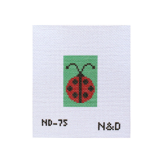 Cross-stitched ladybug design on fabric with 'ND-75' and 'N&D' text.