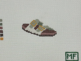 Cross-stitched design of a shoe on fabric with a grid pattern.