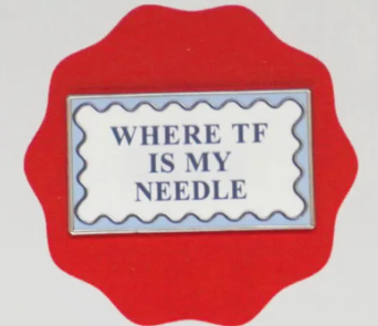 Red frame with a white label inside, containing text 'WHERE IF IS MY NEEDLE' on a light gray background.