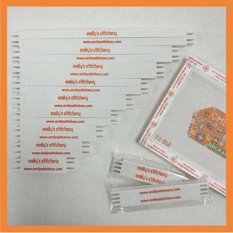 Sheets of fabric with 'emily's stitchery' branding on a textured surface.