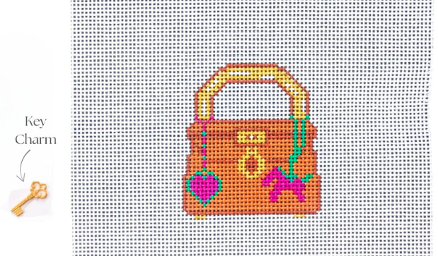 Cross-stitched design of a handbag with key charm on a grid background