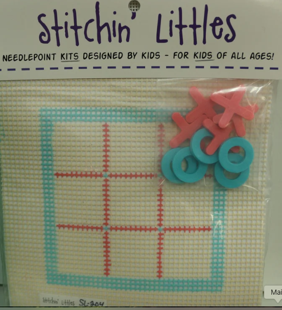 Stitchin' Littles needlepoint kit with red and blue plastic stitchers on a white background