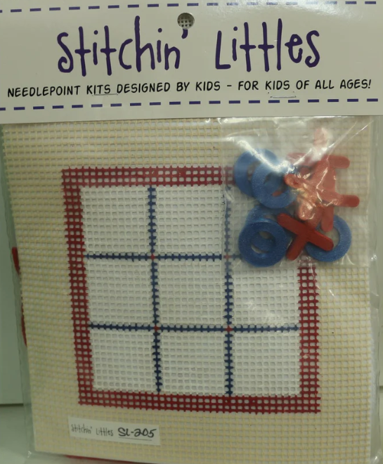 Stitchin' Littles needlepoint kit packaging with cross-stitched design and yarn balls.