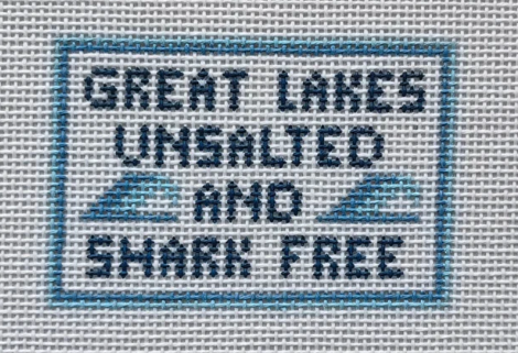 Text 'GREAT LAKES UNSALTED AND SHARK FREE' on a cross-stitched pattern.