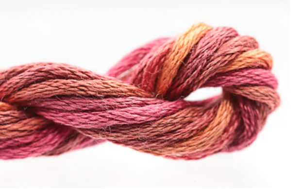 Close-up of a skein of pink and orange yarn on a white background