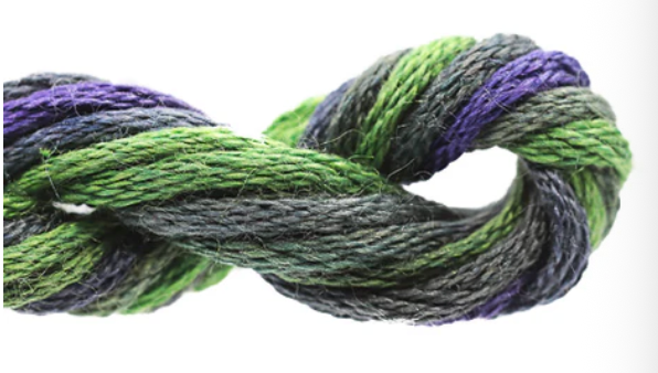 Close-up of green and purple yarn twisted together on a white background