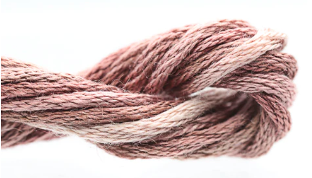 Coiled skein of pink and beige yarn on a white background