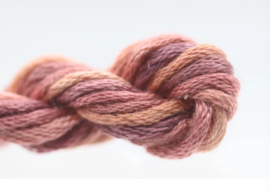 Braided skein of yarn in brown and pink tones on a white background