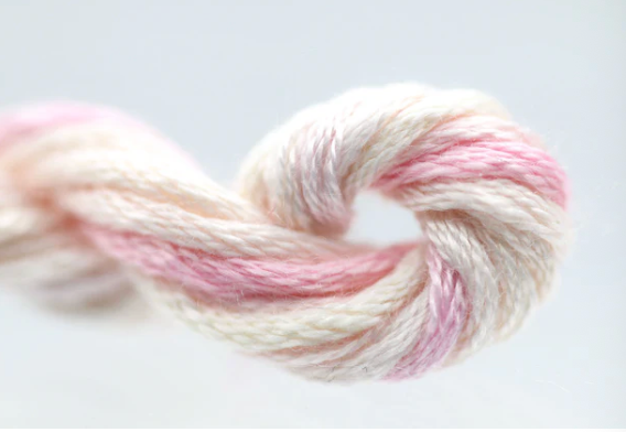 Pastel pink and white skein of yarn on a light gray background