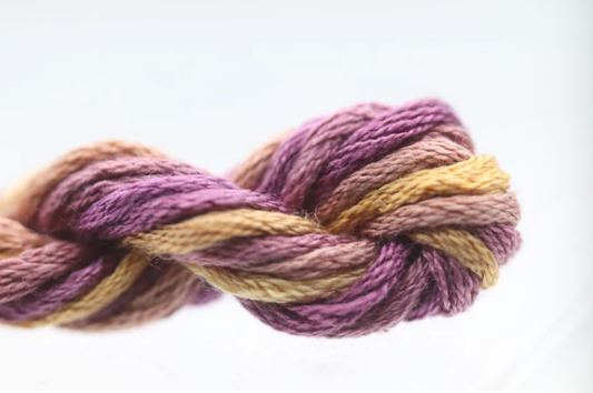 Close-up of a skein of purple and yellow yarn on a white background
