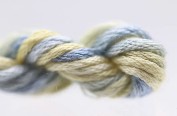 Close-up of a skein of yarn with blue and yellow tones on a light background