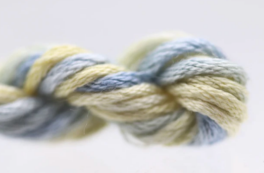 Close-up of a skein of yarn with blue and yellow tones on a light background