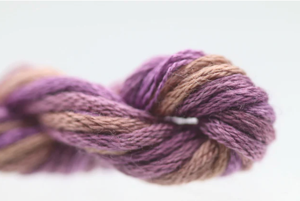 Close-up of a skein of purple and brown yarn on a light background
