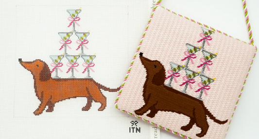 Cross-stitched design of a dachshund and Christmas trees on fabric with a white background.