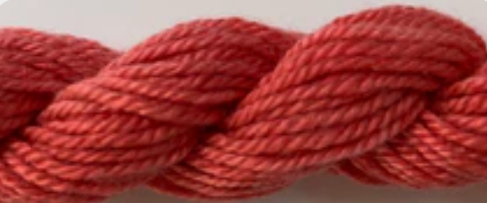 A close-up of a twisted skein of yarn in a dusty rose or muted red-pink color.