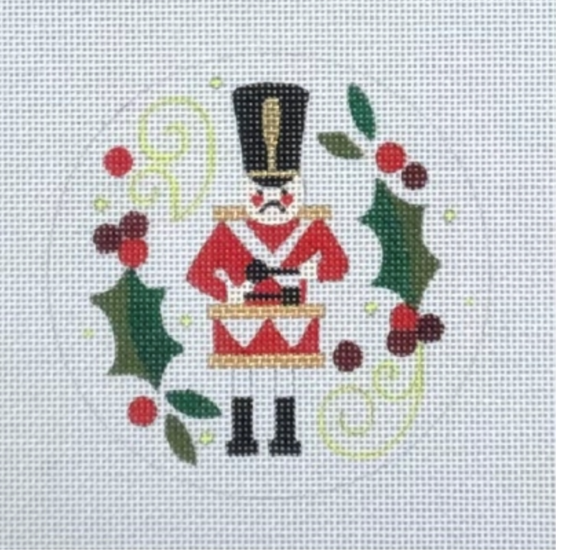 Nutcracker soldier in red uniform and black hat with holly berries